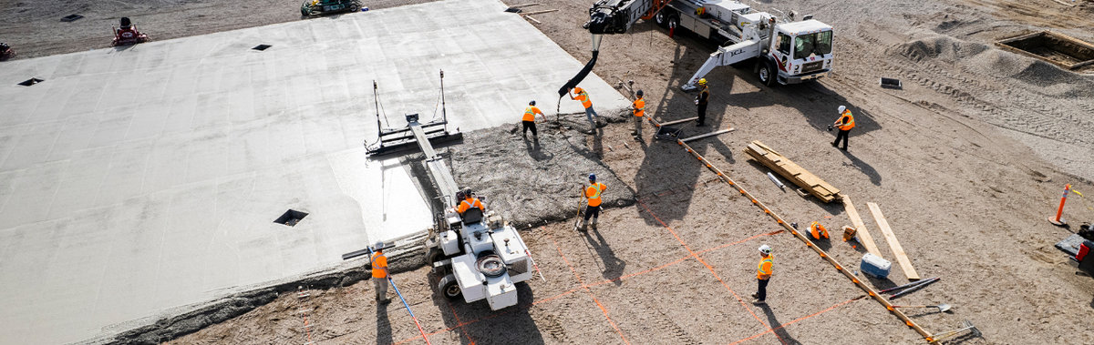 Workers pouring concrete parking lot.