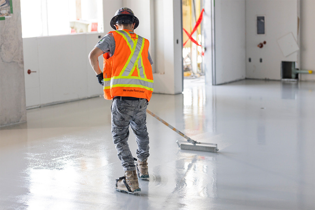 man in high visibility vest working on concrete floor rear shot